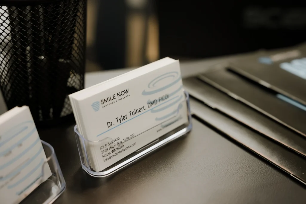 Business cards for Dr. Tyler Tolbert, DMD FICOI sitting on a black desk